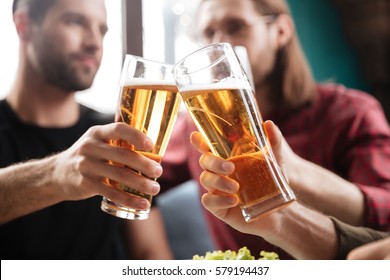 Image of young friends sitting in cafe while drinking alcohol. Focus on glasses of beer. - Powered by Shutterstock