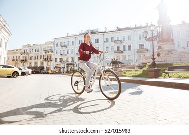 도시에서 스웨터를 입은 젊은 여학생이 자전거를 타고 걸어가는 모습. 스톡 사진