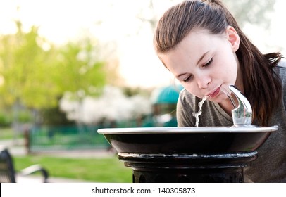 An image of a young girl drinking from a water fountain - Powered by Shutterstock