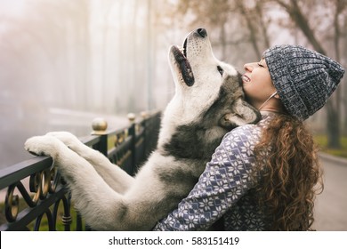 Image Of Young Girl With Her Dog, Alaskan Malamute, Outdoor At Autumn Or Winter. Domestic Pet. Husky