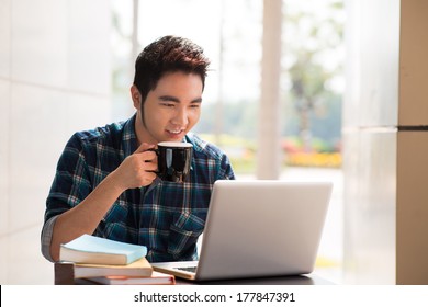 Image of a young guy drinking coffee while computing at a student cafe