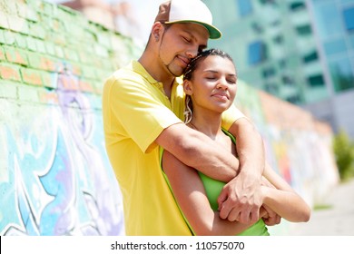 Image of young guy embracing his girlfriend in urban environment