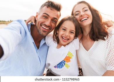 Photo de jeune famille heureuse à l'extérieur sur la plage, prise d'un selfie en caméra. : photo de stock