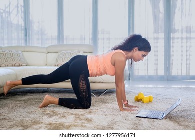 Image Of Young Indian Woman Wearing Sportswear While Doing Yoga Exercises With Laptop At Home