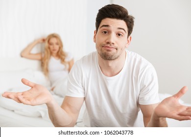 Image Of Young Loving Couple In Bed Indoors At Home Quarrel. Focus On Confused Man.