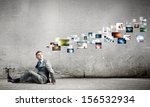 Image of young man sitting on floor looking on media icons