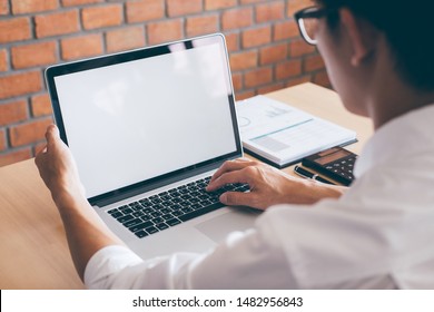 Bild des jungen Mannes, der vor dem Laptop arbeitet und einen Bildschirm mit einem sauberen weißen Bildschirm und Leerraum für Text- und Handschreibinformationen auf der Tastatur im modernen Arbeitsbereich anschaut.