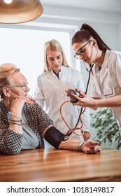 Image Of Young Medic Taking Blood Pressure During Home Visit