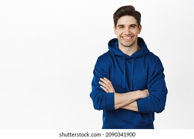 Image of young millennial guy with arms crossed, smiling and looking confident, wearing blue hoodie, white background - Powered by Shutterstock