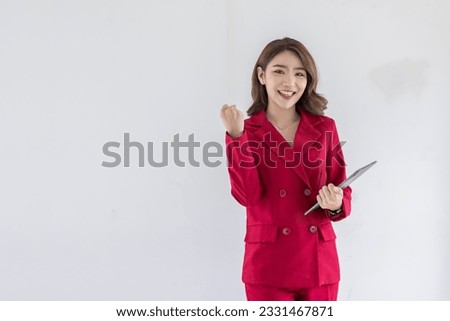 Image of young model asian woman in red suit jacket posing in fashion studio. holding digital tablet, standing over isolated on light white background