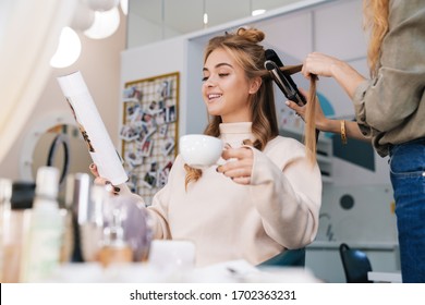 Image of a young pretty blonde girl indoors in beauty salon with hairdresser drinking coffee. - Powered by Shutterstock