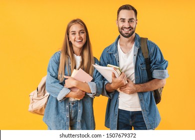 Image of young students in denim clothes smiling while holding exercise books isolated over yellow background - Powered by Shutterstock