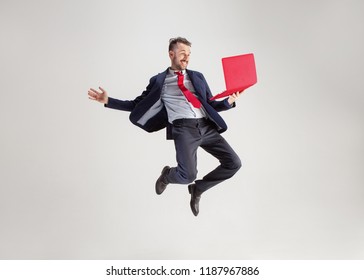 Image of young surprised man over white studio using laptop computer while jumping. illumination in motion