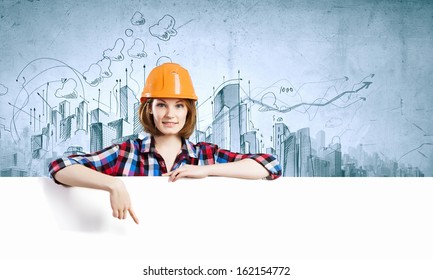 Image of young woman builder wearing helmet and holding blank banner