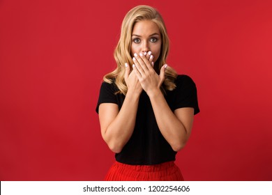 Image of young woman covering mouth isolated over red background.