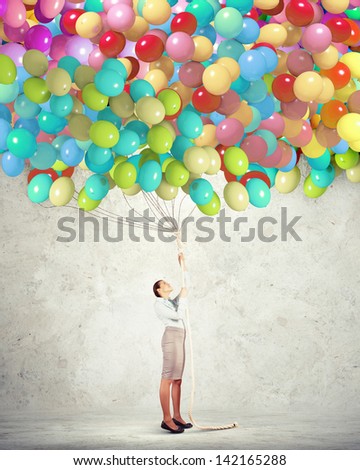 Image of young woman holding bunch of colorful balloons