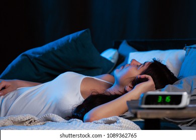 Image of young woman with insomnia lying on bed next to clock - Shutterstock ID 1089362765