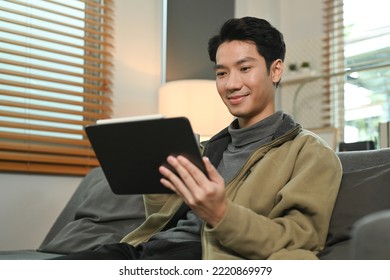 Imaged Of Smiling Man Watching Video On Digital Tablet While Relaxing On Couch At Home