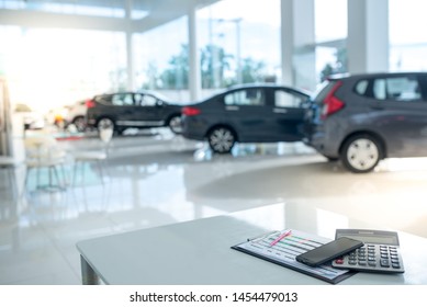 Images in a car showroom with calculators and smartphones placed on a table in the workplace in a new car showroom. The background is a car showroom.