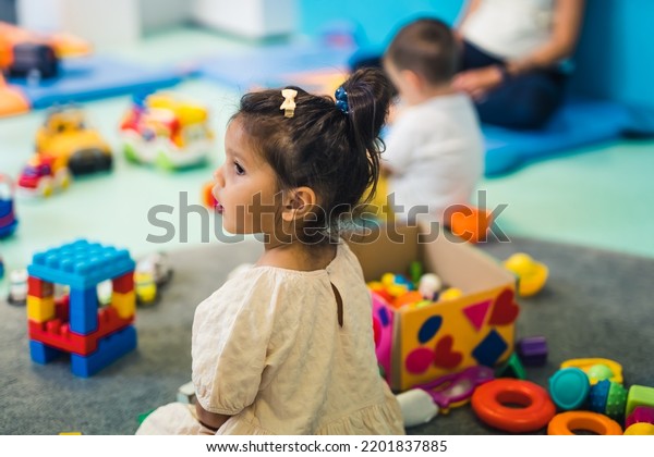 Imagination and creative thinking\
development. Cognitive Growth. Toddlers playing with colorful\
plastic toys and colorful car in a nursery school\
playroom.