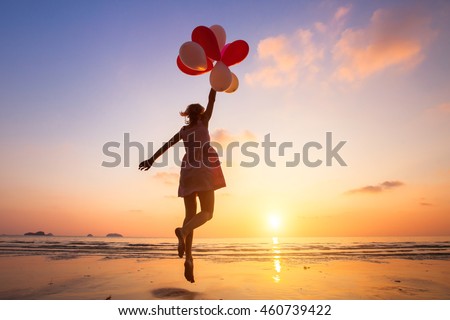 imagination, happy girl jumping with multicolored balloons at sunset on the beach, fly, follow your dream