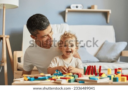 Imaginative storytelling games. Cognitive puzzle challenges. Montessori teaching method. Baby girl playing sorter with her father in living-room.