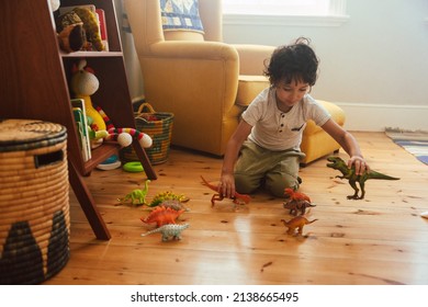 Imaginative Young Boy Playing With Colourful Dinosaur Toys In His Play Area At Home. Adorable Little Boy Kneeling On The Floor While Playing A Fight Game With Animal Toys.