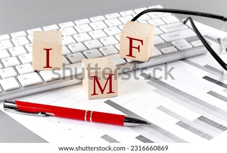 IMF International Monetary Fund written on a wooden cube on the keyboard with chart on a grey background