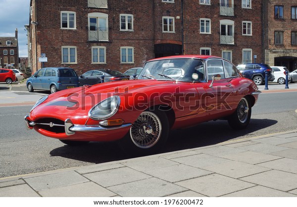 An immaculate red E-Type\
Jaguar car parked on the side of a road in Boston Lincolnshire. May\
5, 2121