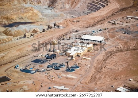The immense scale of a copper mine and its processing plant in Chile, located in an arid environment with the open pit visible in the background.