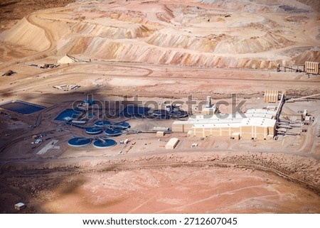 The immense scale of a copper mine and its processing plant in Chile, located in an arid environment with the open pit visible in the background.