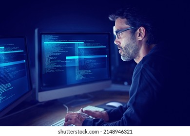Immersed in the metadata. Shot of a focussed computer hacker using a computer in the dark. - Shutterstock ID 2148946321