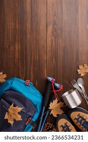 Immersing in a fall foliage adventure in the great outdoors. Top view vertical photo of metal utensils, cozy boots, hiking bag, trekking sticks, cones, fallen leaves on wooden background with ad spot - Shutterstock ID 2366534231