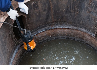 Immersion of the drainage pump in a cesspool filled with contaminated water with feces, pumping of household waste, human sewer, close-up.