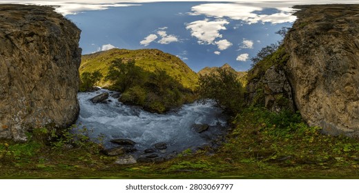 Immersive 360-degree equirectangular panorama captures a turbulent mountain river flowing through a rocky gorge in Kyrgyzstan. Lush greenery and steep cliffs frame the swift current, illuminated by bright daylight.