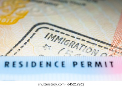 Immigration concept image. Residence permit card over immigration stamp on UK visa in passport. Selective focus - Shutterstock ID 645219262
