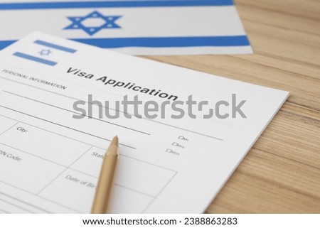 Immigration to Israel. Visa application form, pencil and flag on wooden table, closeup