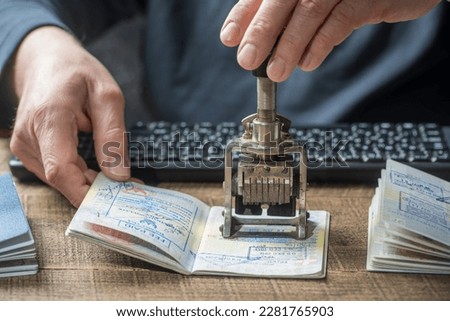 Immigration and passport control at the airport. Man border control officer puts a stamp in the international passport, close up. Vacation and travel concept