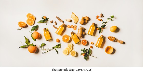 Immune boosting natural vitamin health defending drink to resist virus. Flat-lay of fresh turmeric, ginger and citrus juice shots over white background, top view. Vegan Immunity system booster - Shutterstock ID 1695777016