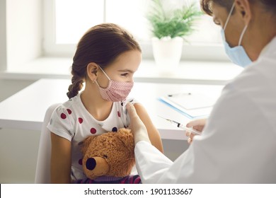 Immunization For Children Concept. Happy Little Kid Holding A Toy And Getting A Flu Shot Not Afraid Of The Syringe Needle. Doctor Injecting Brave Child With Covid-19 Vaccine At Clinic Or Hospital