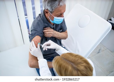 Immunization of elderly population. Close up view of an elderly man being vaccinated in his arm during corona virus pandemic.