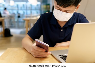 The Impact Of Digital Technology Use On Adolescent Well-being Concept. A Smart Asian Teenager Boy With Face Mask Using A Smartphone And Laptop Computer In A Canteen. Tech, Teen Mental Health, Digital.