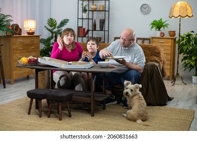 An impatient dog looks around for a second pizza. The family consumes the pizza.