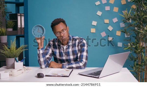 Impatient man\
waiting to finish work and checking time on clock, feeling tired\
and displeased. Serious upset person looking at watch to see\
deadline delay and time before\
break.