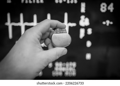 An Implantable Pacemaker Is Held In Front Of An ECG Monitor 