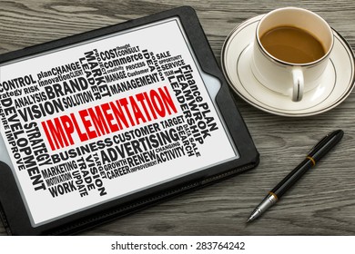 implementation concept with business word cloud on tablet pc