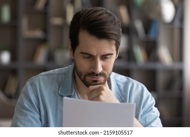 Important letter. Concentrated serious male small business owner think ponder on bank report analyze sales using printed statistic information. Pensive young businessman doing paperwork at home office - Shutterstock ID 2159105517