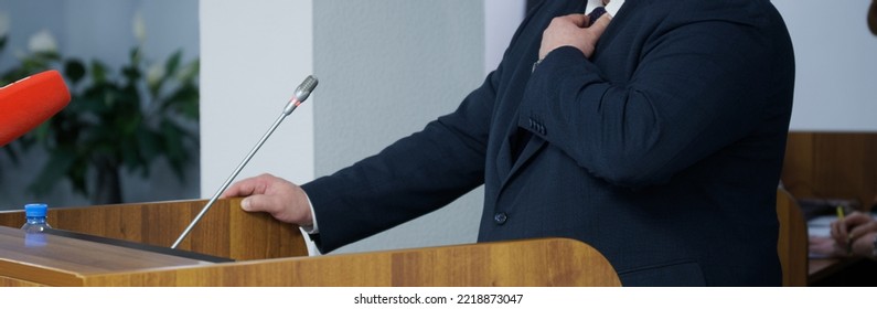 An Important Man - A Lawyer, Businessman, Politician, Or Official Straightens His Tie, Speaking From The Podium. Official Statement. Orator, Speaker Or Interviewee. Selective Focus. No Face