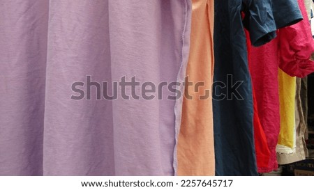 Imported Branded Clothes Mixed In Second-Hand Condition Are Hung In Rows With Hangers. Collection Used For Selling and Thrifting Trends. Colorful Clothes. There Are Linen, Cotton, Jeans, and Wool