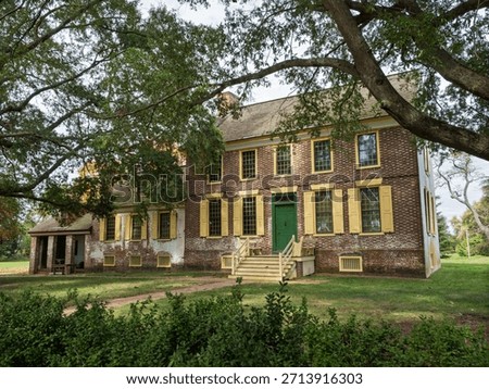 The imposing front facade of the main house at John Dickinson Plantation featuring brickwork, yellow shutters, and a green door.